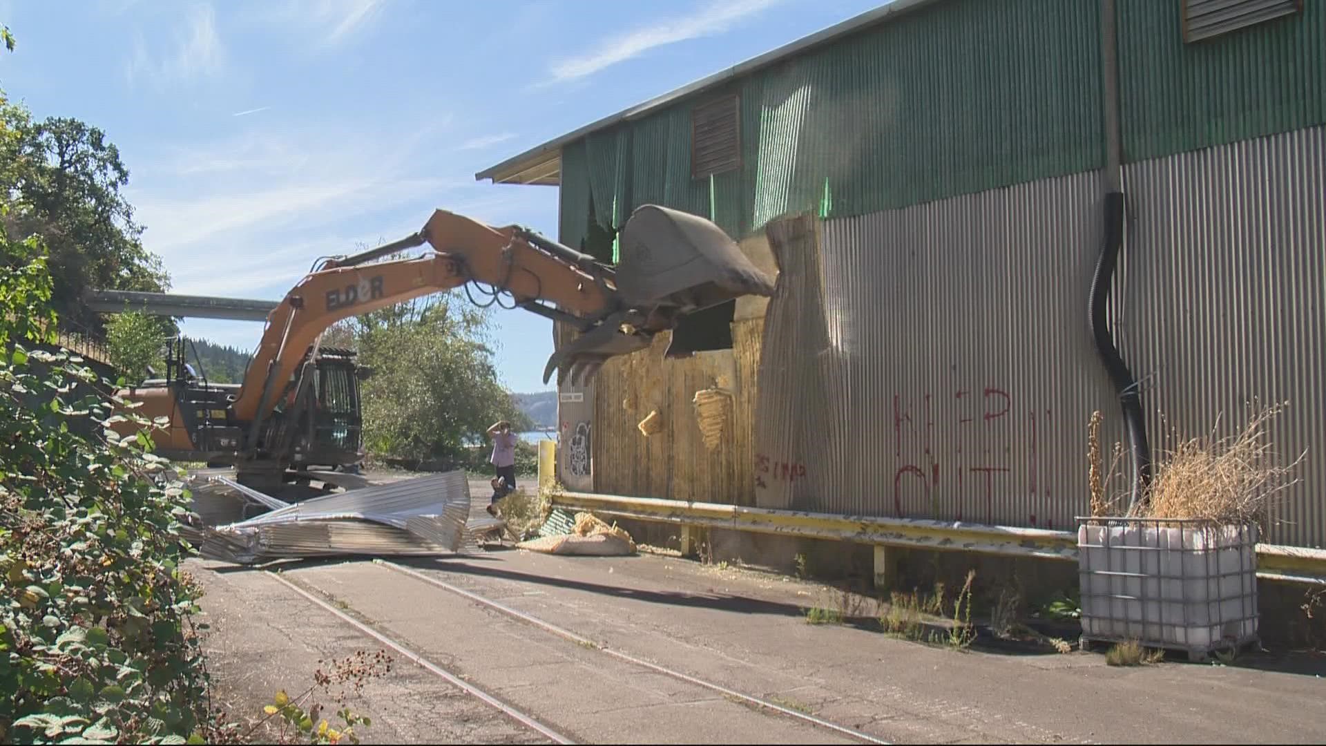 Crews began tearing the walls off one of the buildings at the site, which will eventually become a mixed-use development.