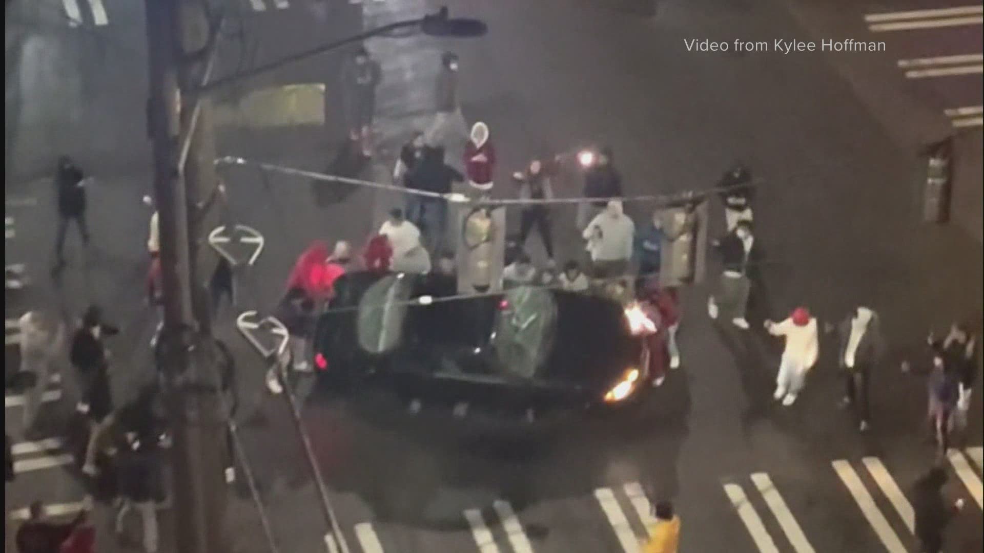 Video shared on social media and with KING 5 shows a large group of people in the University District flipping and destroying a car during a street racing event.
